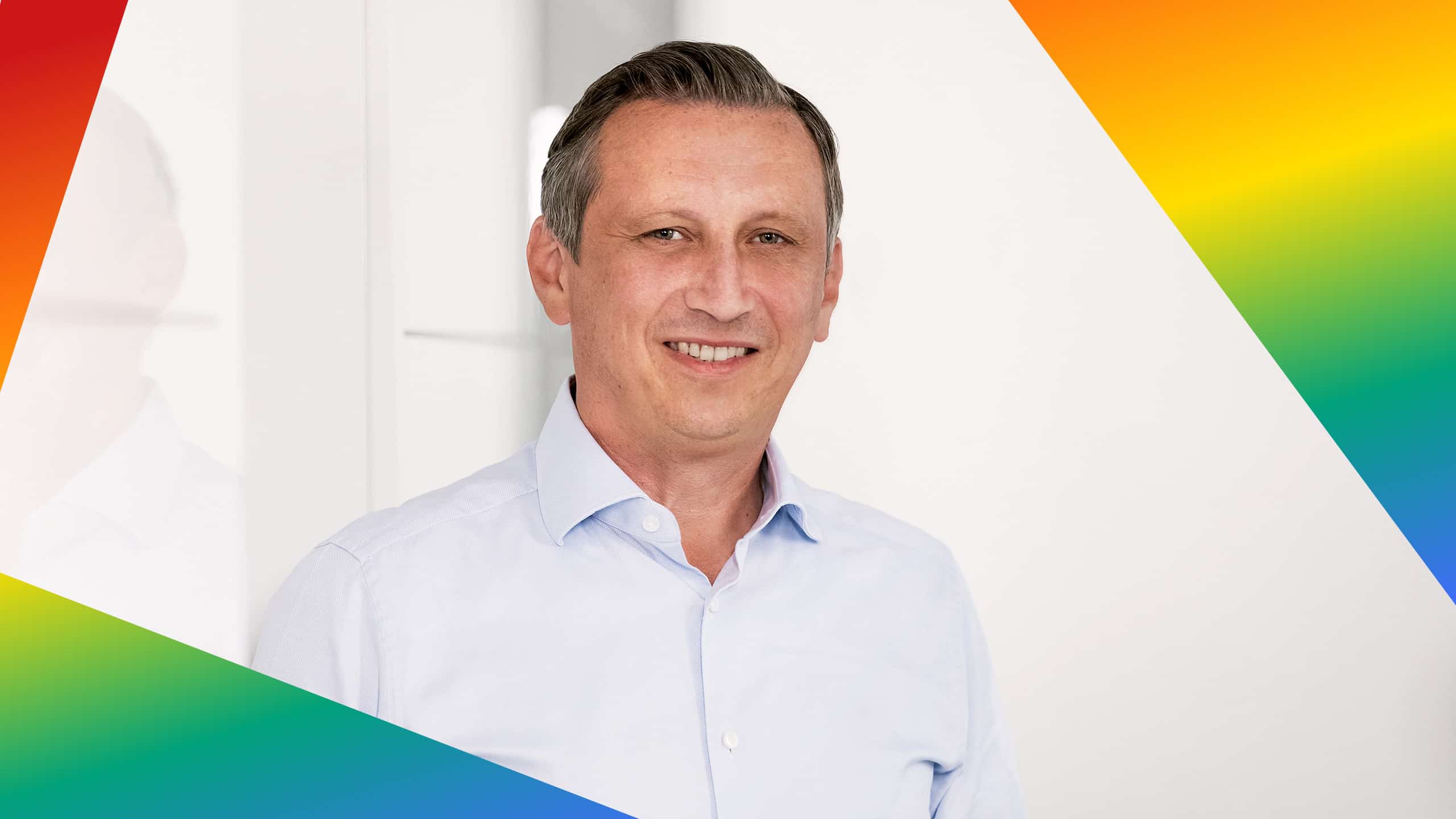Porträt von Lionel Souque in einem Rahmen in den Farben der LGBTQIA+ Bewegung