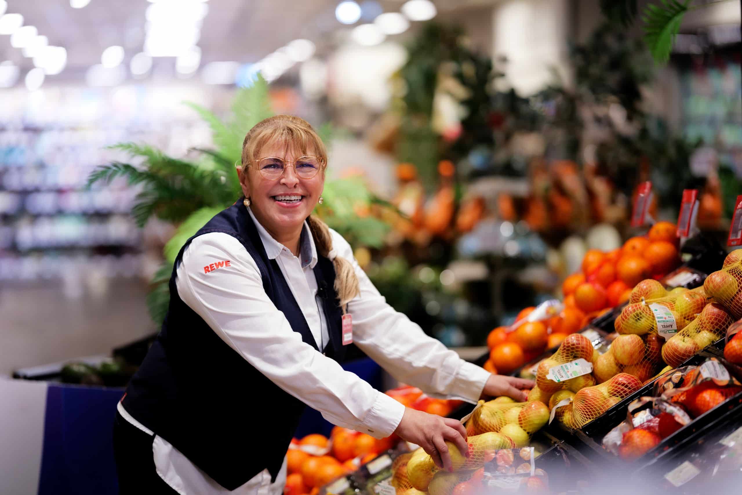 Auf dem Bild ist Debora Agelidu zu sehen. Sie steht an einer Obst- und Gemüseauslage in einem Supermarkt.