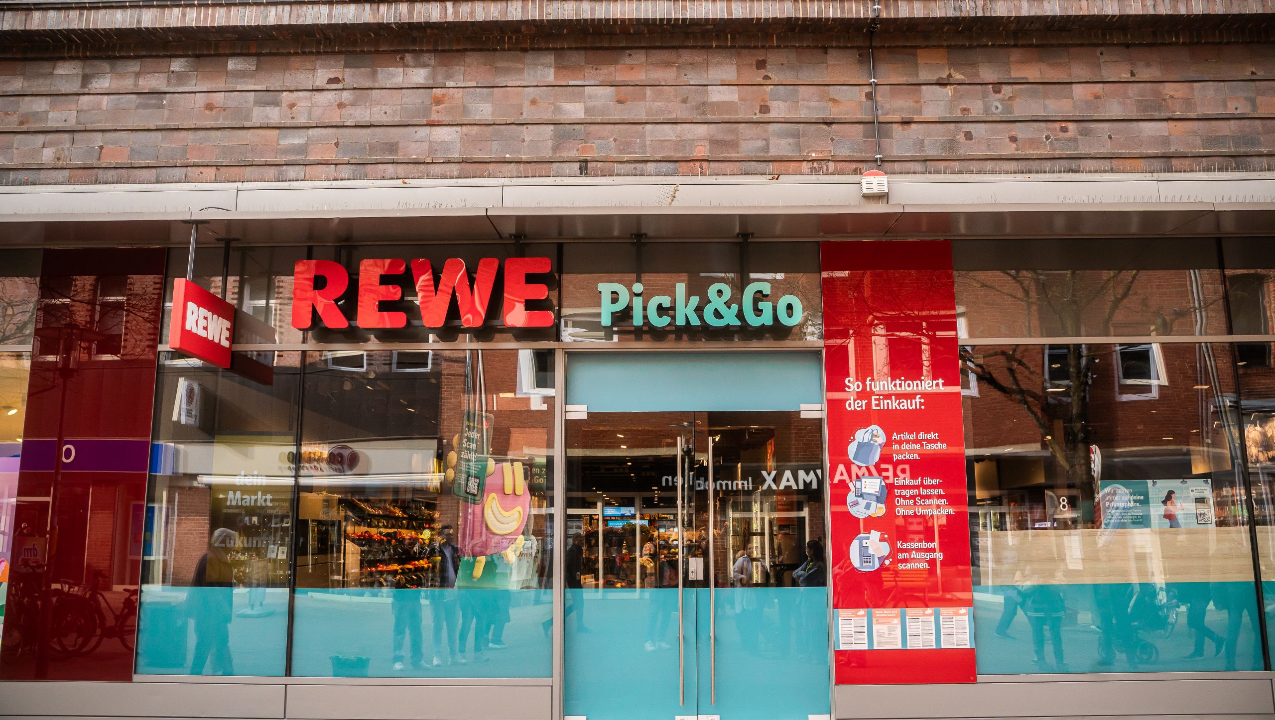 Das Bild zeigt den Eingang eines Geschäfts mit großen Leuchtschildern, auf denen 