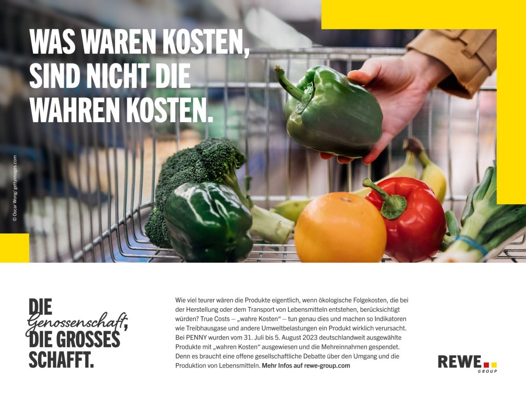 Nahaufnahme eines Einkaufswagens mit frischem Obst und Gemüse, während eine Hand eine grüne Paprika hält, begleitet von einem großen Text: 