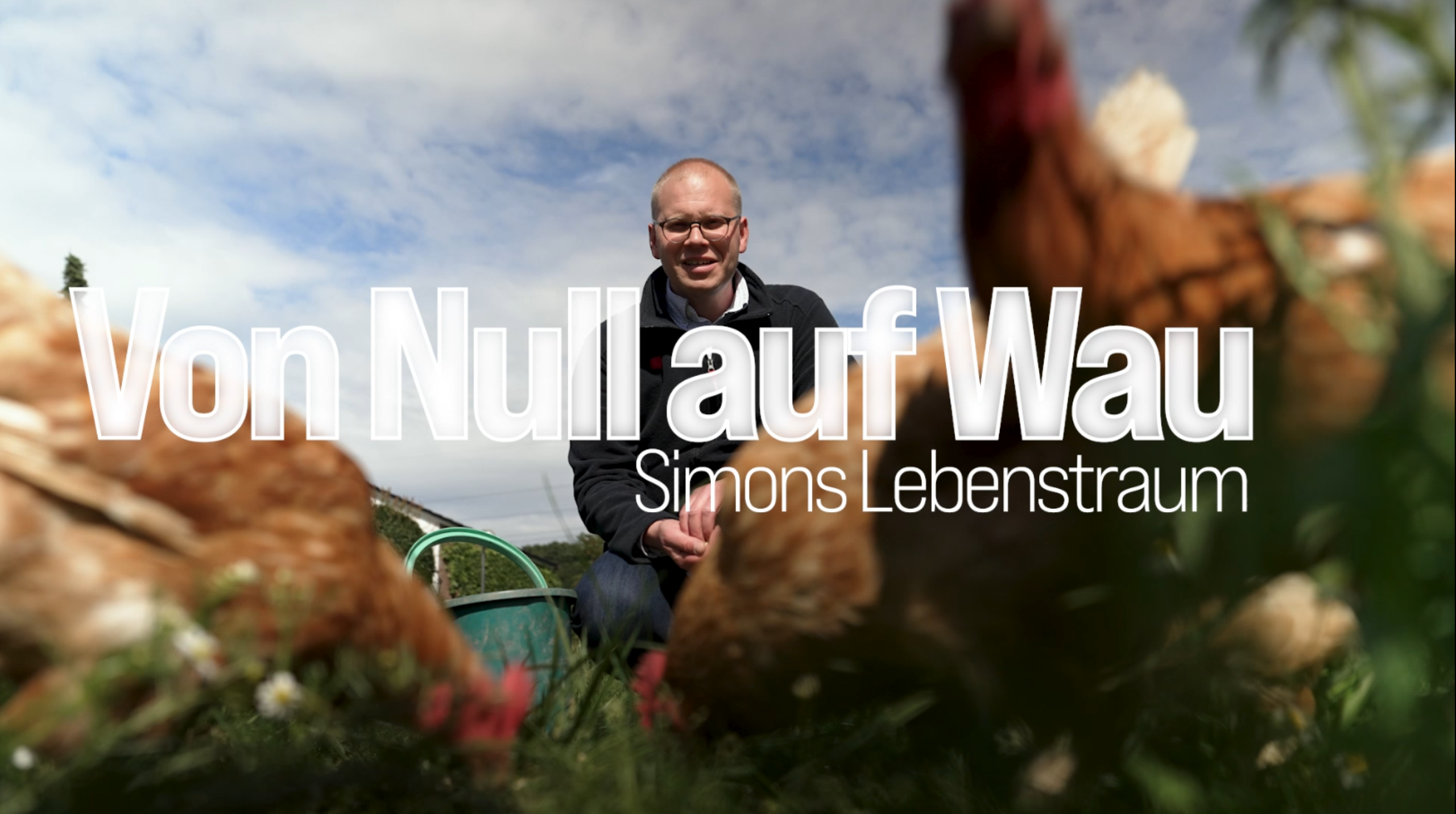 Simon Bacher, a REWE store manager, sits in a meadow surrounded by free-range chickens; the title “From Zero to Wau—Simon’s Lifelong Dream” appears on screen.