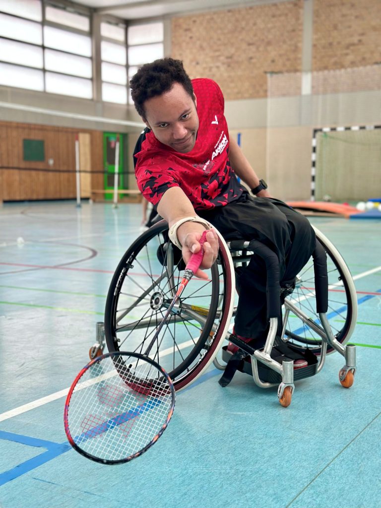 Para-Badminton-Europameister Rick Hellmann spielt Badminton im Rollstuhl in einer Sporthalle.