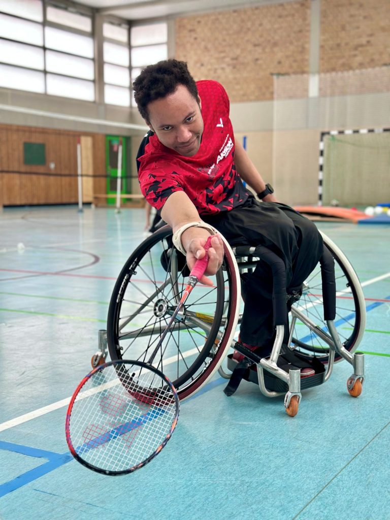European Para-Badminton Champion Rick Hellmann plays wheelchair badminton in a sports hall.