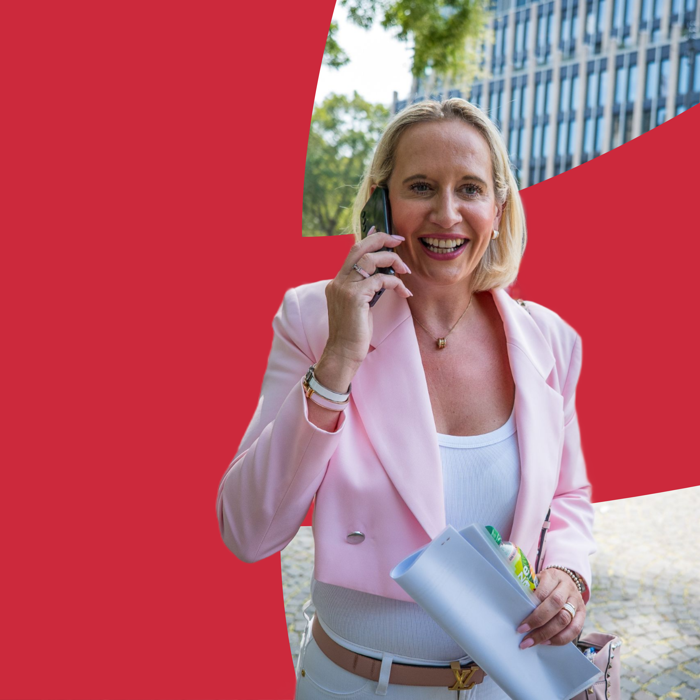 Marika Schaible im hellrosa Blazer telefoniert auf einem Platz vor modernen Bürogebäuden.