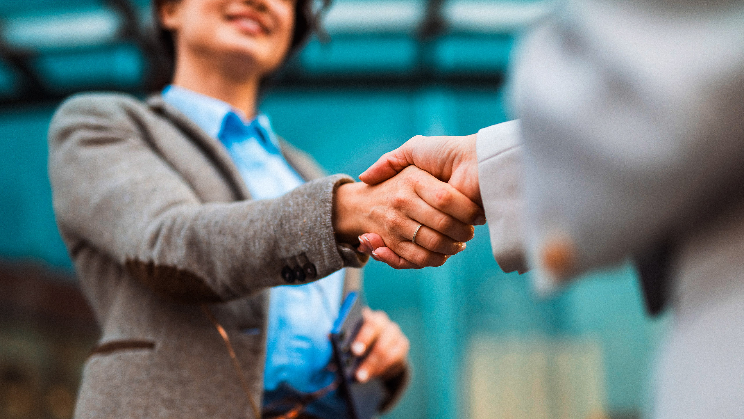 Nahaufnahme eines Händedrucks zwischen zwei Personen in einer geschäftlichen Umgebung.