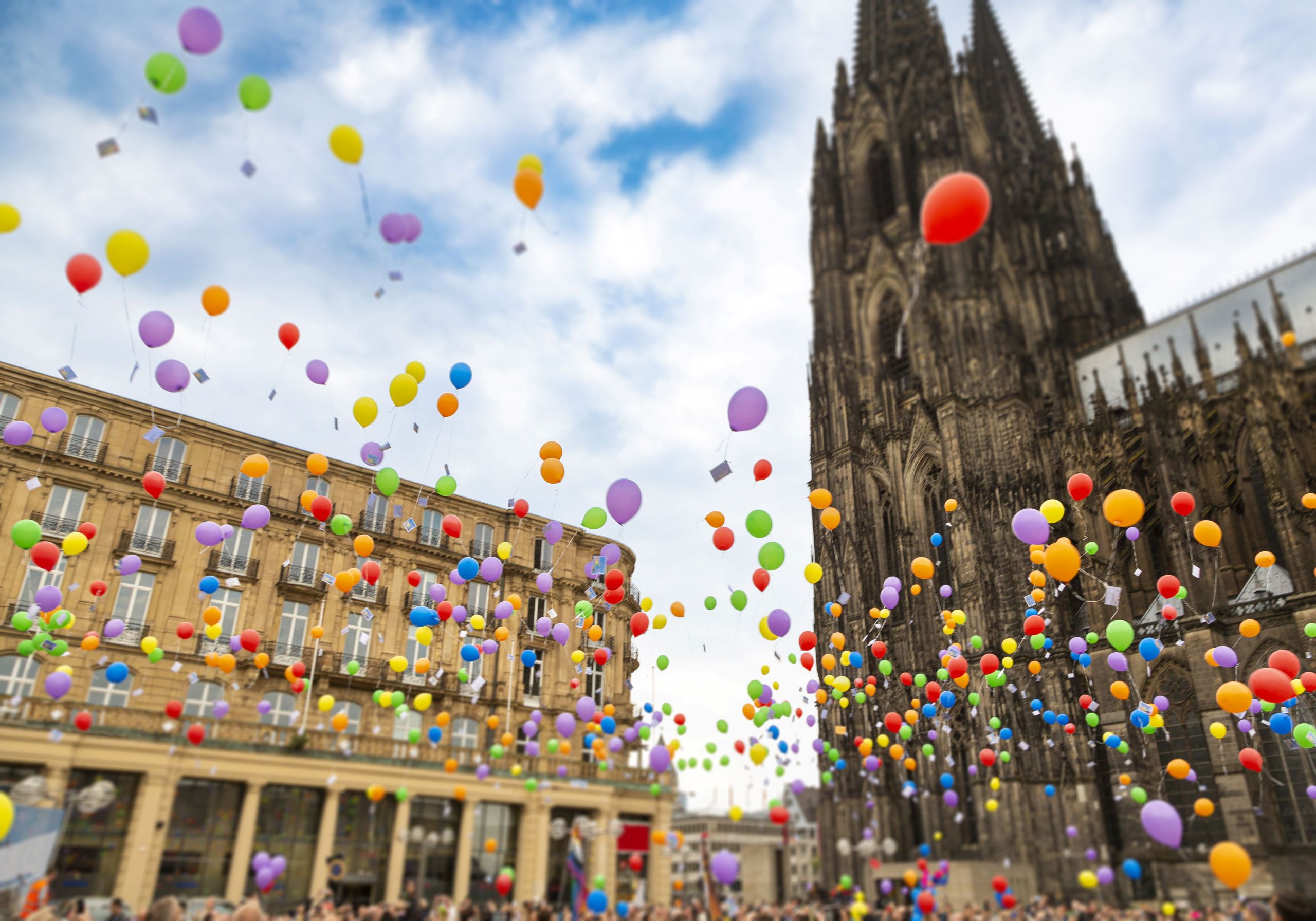 Bunte Luftballons steigen vor dem Kölner Dom in den Himmel.