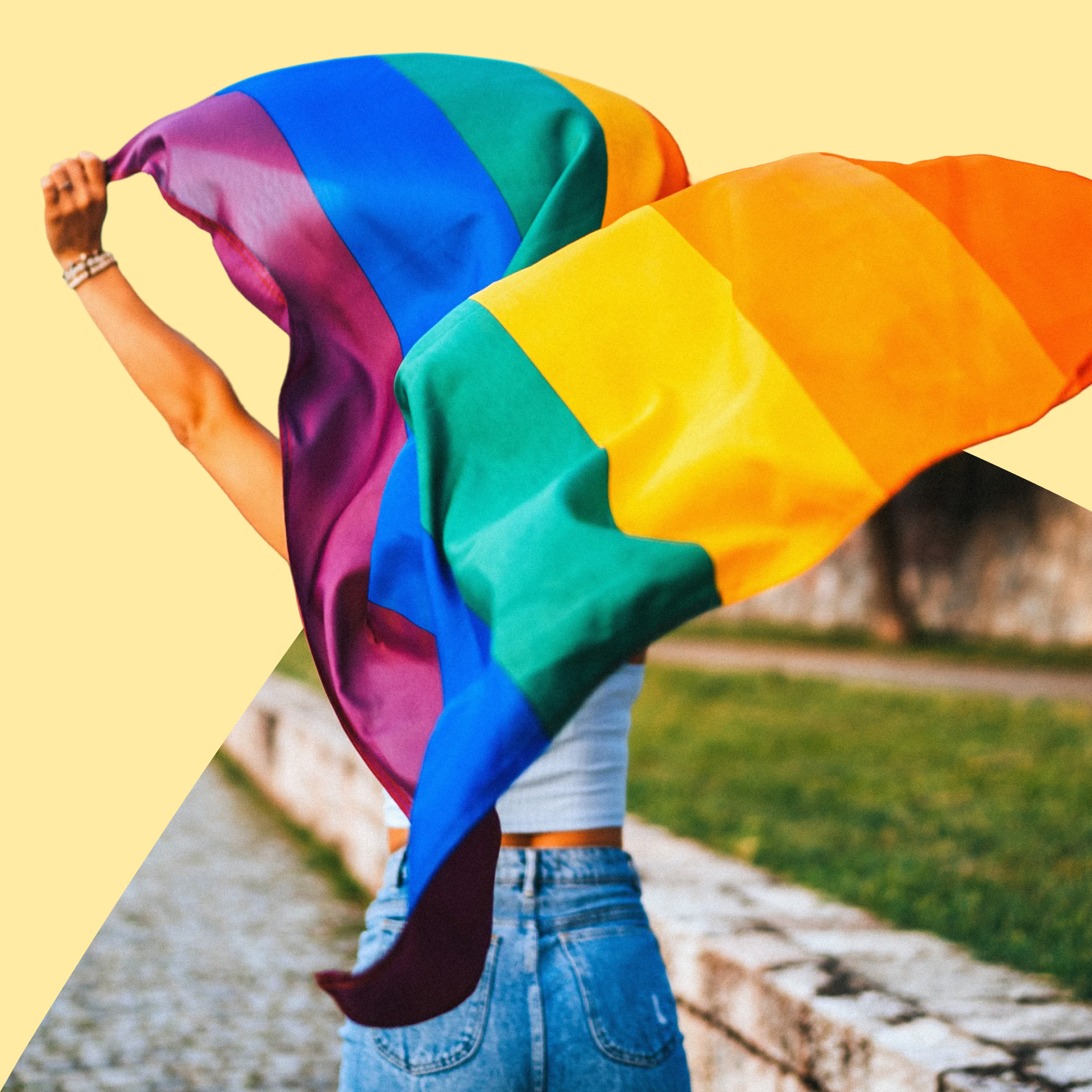 Person hält eine große Regenbogenflagge über dem Kopf, die sich im Wind ausbreitet. Das Foto ist teilweise von einer hellgelben grafischen Fläche eingerahmt.